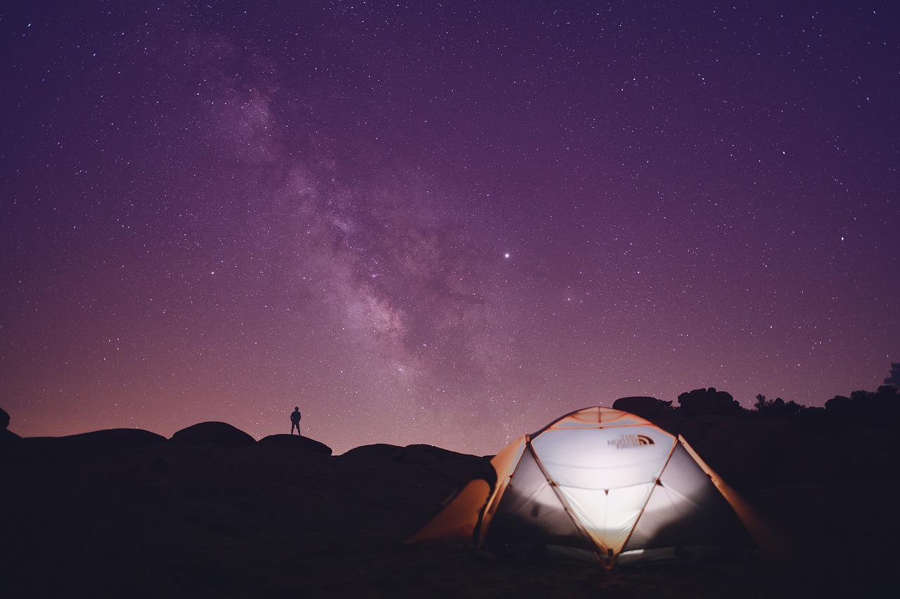Tent glowing at night under a starry sky